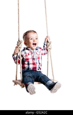 Happy little boy swinging sur une balançoire en bois Banque D'Images