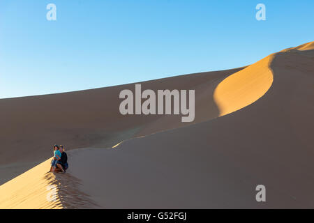 La Namibie, Sossusvlei, Hardap, mère avec fils sur une sandberg dans le désert, escalade la Dune Big Daddy au lever du soleil Banque D'Images