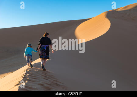 La Namibie, Sossusvlei, Hardap, mère avec fils de marcher dans le désert, escalade la Dune Big Daddy au lever du soleil Banque D'Images