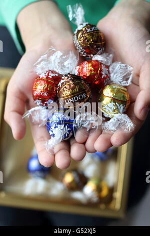 Close up of hand holding assortiment de chocolats Lindt Lindor en emballage métallique Banque D'Images