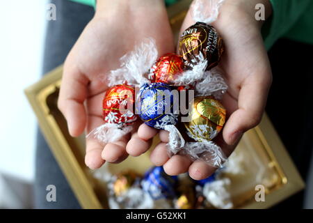 Close up of hand holding assortiment de chocolats Lindt Lindor en emballage métallique Banque D'Images