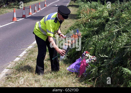 Un agent de police de Sussex place des fleurs sur les lieux par l'A29, où le corps d'une jeune fille a été trouvé dans un champ au nord de Pulborough, dans le Sussex.On croit que c'est celui de Sarah Payne, âgée de huit ans, qui a disparu il y a seize jours. Banque D'Images