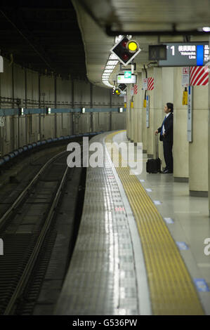 Commis de bureau en attente d'un train JR sur une plate-forme à Tokyo Banque D'Images