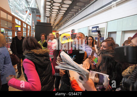 Justin Bieber (casquette jaune) est pris par les fans alors qu'il arrive au terminal 5 de l'aéroport d'Heathrow avant le lancement de son album. Banque D'Images