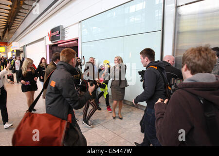 Justin Bieber (casquette jaune) est pris par les fans alors qu'il arrive au terminal 5 de l'aéroport d'Heathrow avant le lancement de son album. Banque D'Images