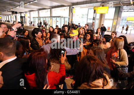 Justin Bieber (casquette jaune) est pris par les fans alors qu'il arrive au terminal 5 de l'aéroport d'Heathrow avant le lancement de son album. Banque D'Images