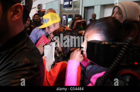 Justin Bieber (casquette jaune) est pris par les fans alors qu'il arrive au terminal 5 de l'aéroport d'Heathrow avant le lancement de son album. Banque D'Images