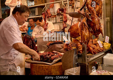 Un boucher prépare certaines cha-siu les aliments cuits à une boutique sur Shanghai Street à Yau Ma Tei, Hong Kong. Banque D'Images