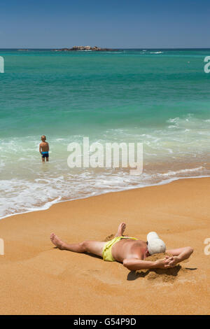 Sri Lanka, Galle Province, Unawatuna beach, sur le sable et sunbather jeune garçon en bas-fonds Banque D'Images