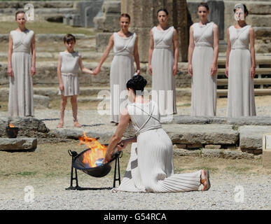 La flamme olympique est éclairée par une actrice habillée comme la haute prêtresse, utilisant un miroir parabolique pour refléter les rayons du soleil, lors d'une répétition pour la cérémonie de demain, Ce qui indique au monde que le compte à rebours des Jeux de Londres 2012 a commencé, au Temple de Hera à Olympia, en Grèce, où les Jeux Olympiques anciens ont eu lieu. Banque D'Images