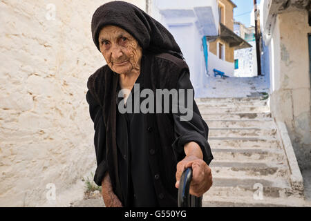 Une femme marche à l'aide d'une canne, à travers le village d'Anogia, sur l'île de Crète en Grèce Banque D'Images