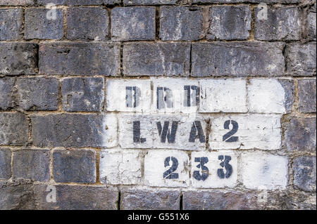 Mur de briques de la station de chemin de fer avec des chiffres et des lettres, en noir sur fond blanc Banque D'Images