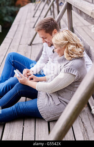 Jeune couple heureux mari et femme enceinte se détendre sur un banc Banque D'Images