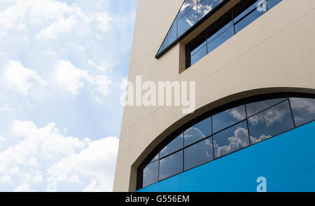 De mur jaune crème et bleu foncé avec de gros bâtiment fenêtre claire reflétant ciel nuageux Banque D'Images