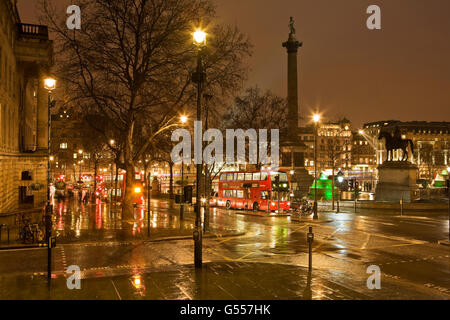 Londres, Angleterre, Trafalgar Square la nuit sous la pluie avec des bus à double étage Banque D'Images