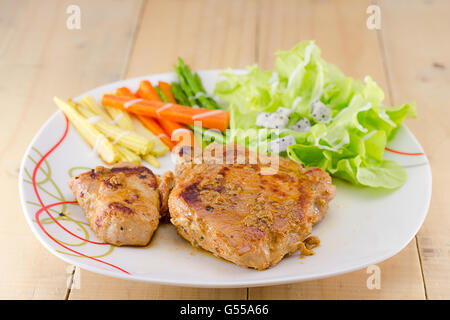 Les steaks grillés sur un plat blanc avec salade Banque D'Images