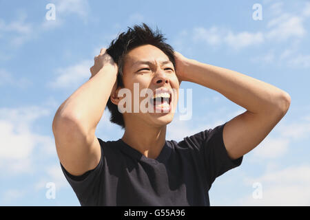 Jeune homme japonais cheering contre le ciel bleu Banque D'Images