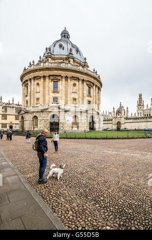 Oxford, Royaume-Uni - 14 août 2015 : femme jouant avec son chien près de Radcliffe Camera à Oxford un jour nuageux Banque D'Images