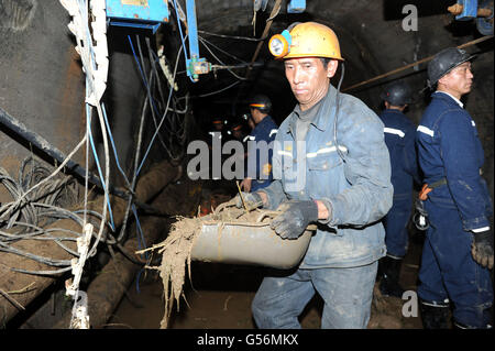 Qianxinan, province du Guizhou en Chine. 21 Juin, 2016. Un sauveteur porte-nouvellement dragué de limon et d'articles divers dans le tunnel de la mine de charbon en Nasheng Dingxiao Township, au sud-ouest de la province du Guizhou, en Chine, le 21 juin 2016. Jours de pluie torrentielle a abouti à une rivière près de la mine de charbon en Nasheng Dingxiao Canton de Guizhou Province briser ses rives, le piégeage huit mineurs qui travaillaient sous terre dans un arbre, a déclaré que l'Administration d'état de la sécurité au travail. Un pont d'urgence d'entrer dans la zone des mines de charbon a été construit. Le dragage et le drainage est en cours. © Tao Liang/Xinhua/Alamy Live News Banque D'Images