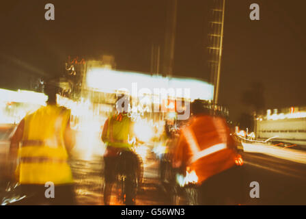 Photographie de certains blured d'éclairage sur une scène urbaine de nuit et certains cyclistes silhouettes Banque D'Images