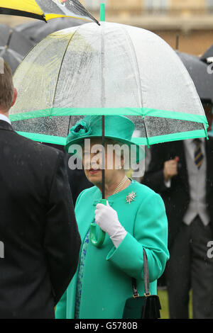 La reine Elizabeth II de Grande-Bretagne se protège de la pluie sous un parapluie alors qu'elle organise une fête dans le jardin au palais de Buckingham, dans le centre de Londres. Banque D'Images