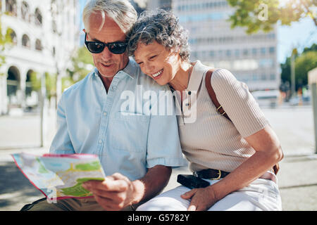 Couple à la recherche d'un plan de la ville. Deux aînés reading a map ensemble alors qu'il était assis dehors sur un banc. Banque D'Images