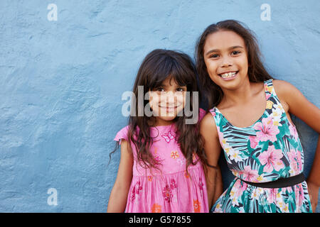 Portrait de deux petites filles se tenant ensemble contre fond bleu. Adorable petit friends posing together avec sourire mignon. Banque D'Images