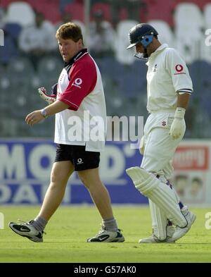 Angleterre physio Dean Conway (à gauche) dirige le skipper d'Angleterre Nasser Hussain hors du champ après qu'il a été frappé sur le bras par une balle de Wasim Akram du Pakistan pendant la dernière journée du Premier Test entre l'Angleterre et le Pakistan à Lahore. Banque D'Images