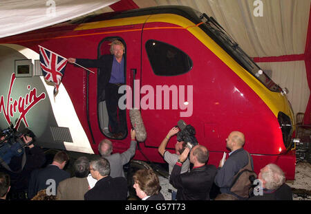 Sir Richard Branson fait le drapeau de l'Union lors du lancement de son nouveau train Virgin train Maiden Voyager à Bruges, en Belgique.*05/03/01 les tarifs ferroviaires des trains Virgin augmenteront de près de 10% à la suite de la catastrophe de Hatfield, a confirmé la société.Les passagers qui ont subi des mois de retard sur le réseau ferroviaire devront payer les prix des billets à partir de mai.Virgin a déclaré qu'elle regrettait l'augmentation et a accusé Railtrack de ne pas avoir fourni une compensation adéquate pour les perturbations causées par l'accident de Hatfield. Banque D'Images