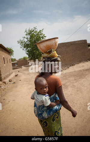 Une femme porte un enfant sur le dos à Niassan, village du Burkina Faso. Banque D'Images