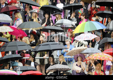 Les Racegoers se réfugient à l'abri de la pluie alors qu'ils attendent l'arrivée de la reine Elizabeth au cours du troisième jour de la réunion de 2012 de la Royal Ascot à l'hippodrome d'Ascot, dans le Berkshire. Banque D'Images