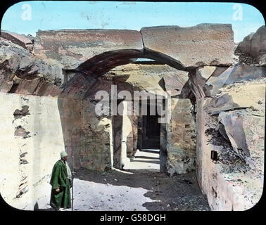 Die Halten der Hindurch ern wir zu den Kammern, die einst ernst und wuchtig das auf der heiligen Barke thronende Götterbild umschlossen haben. Nun huschen Eidechsen im Sand. Unter viel Aufwand Hat man diesen Tempel aus dem alles verwehenden Wüstensand herausgegraben und völlig freigelegt, während der einige Meilen nilaufwärts gelegene Hathortempel noch im Sande von Dendera steckt. Égypte, Abydos, Afrique, Moyen-Orient, histoire, historique, 1910, 20e siècle, voyage, haute-Égypte, temple complexe, entrée, porte, antique, monument, homme, main couleur verre glissé Banque D'Images