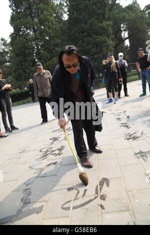 Un chinois d'un calligraphe, utilise la brosse et de l'eau énorme à peindre les caractères chinois sur le sol, près du Temple du Ciel. Beijing, Chine. Banque D'Images