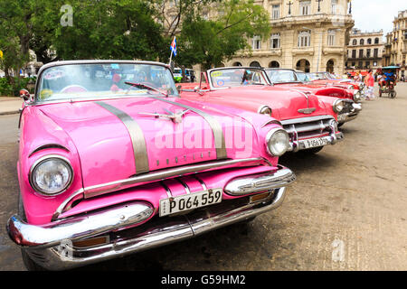 American 1950 Pontiac Star Chief et Chevrolet Classic cars roses et rouges alignés dans le Parque Central, La Vieille Havane, Cuba Banque D'Images