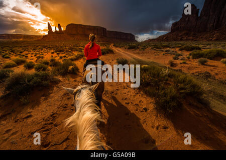 Monument Valley l'équitation première personne vue depuis le cheval avec Ciel de coucher du soleil sur les trois soeurs Banque D'Images