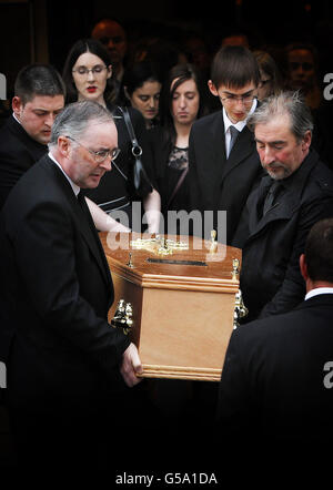 Sean Moloney (à droite) frère du journaliste irlandais Eugene Moloney assassiné, Joseph Moloney (deuxième à droite), John McCoughin (à gauche) et d'autres membres de la famille portent son cercueil de l'église notre Dame de la paix de Dublin après la messe funéraire. Banque D'Images