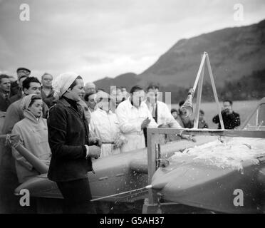 Donald Campbell (au centre des figures surmontées de blanc) est amusé par la grimace de sa femme tandis que Mme Dorothy Campbell (à gauche) éclate une bouteille de champagne contre une structure en bois érigée au sommet de 'Bluebird' pour le baptême de l'artisanat.La scène était le lac Ullswater à Cumberland où Donald prépare son hydravion à turbojet pour sa tentative sur le record mondial de vitesse de l'eau. Banque D'Images