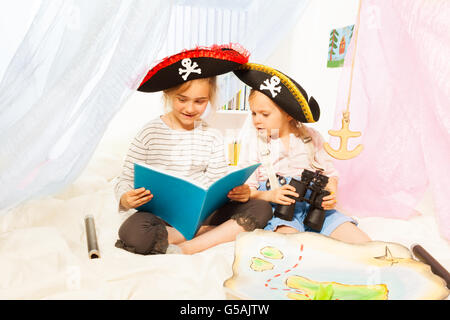 Deux jeunes filles en costumes de pirate fée-conte lecture Banque D'Images