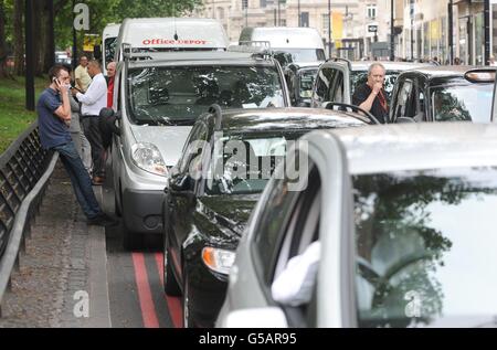 Les chauffeurs se tiennent aux côtés de voitures stationnaires dans un embouteillage sur Park Lane dans le centre de Londres, tandis que les chauffeurs de taxi londoniens protestaient contre une interdiction d'utiliser les voies de circulation olympiques. Banque D'Images