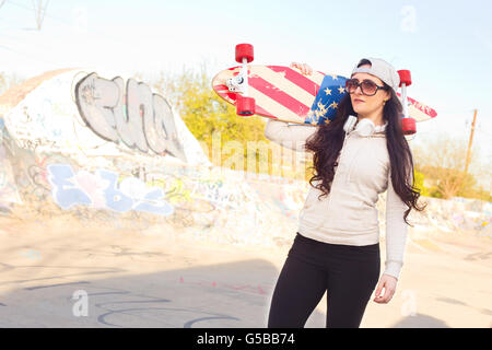 Jeune femme tenant son skateboard Banque D'Images