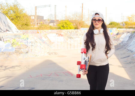 Jeune femme tenant son skateboard Banque D'Images