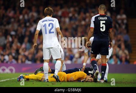 Sungryong Jung, gardien de but sud-coréen, et Micah Richards, en Grande-Bretagne, sont blessés par terre après avoir heurté lors du match de finale du quartier des hommes au Millennium Stadium de Cardiff, le huitième jour des Jeux Olympiques de Londres en 2012. Banque D'Images