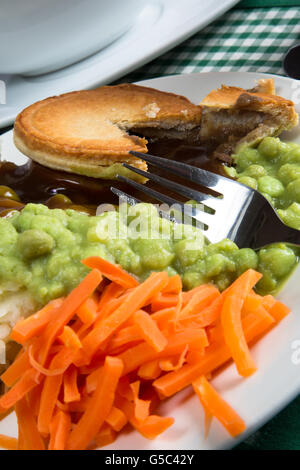 Un plat traditionnel anglais classique de steak Pie, purée de pommes de terre, petits pois et carottes. Servi avec de la sauce. Banque D'Images