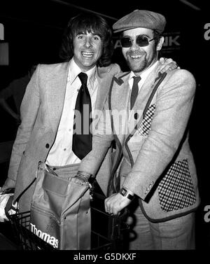 1976: Garder le menton vers le haut après la défaite de l'Angleterre aux mains des Italiens, le footballeur d'Angleterre Stan Bowles (l), accompagné du chanteur Elton John, arrive à l'aéroport d'Heathrow de Rome.Elton, un fan de football, a également géré un large sourire. Banque D'Images