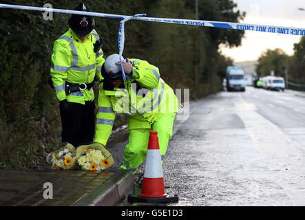 Un policier dépose des fleurs, portées par un membre du public, sur les lieux d'une fusillade à Hattersley, dans le Grand Manchester, au cours de laquelle deux policiers non armés sont morts après avoir assisté à un « incident de routine » qui a conduit à l'arrestation de l'un des hommes les plus recherchés du pays. Banque D'Images