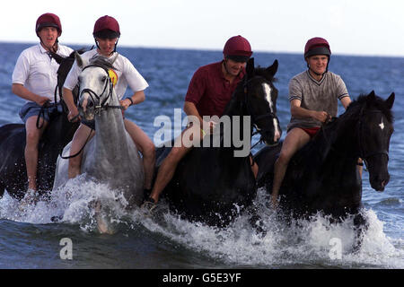 Quatre membres de l'escadron des gardes de vie du régiment monté de cavalerie de la maison exercent leurs chevaux dans les eaux profondes de Holkham Beach à Norfolk pendant les vacances d'été des chevaux. Banque D'Images