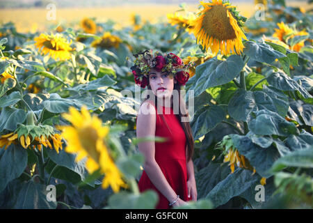 Preteen avec couronne dans un champ de tournesols Banque D'Images