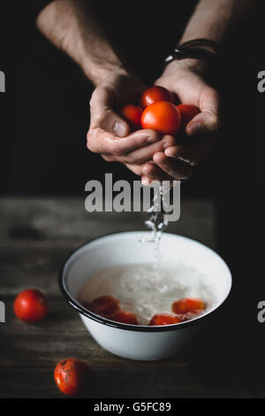 Male chef lave les tomates. Les tomates dans les mains. Banque D'Images