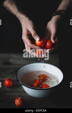 Male chef lave les tomates. Les tomates dans les mains. Banque D'Images