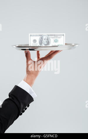 Part of waiter in suit holding tray with money Banque D'Images